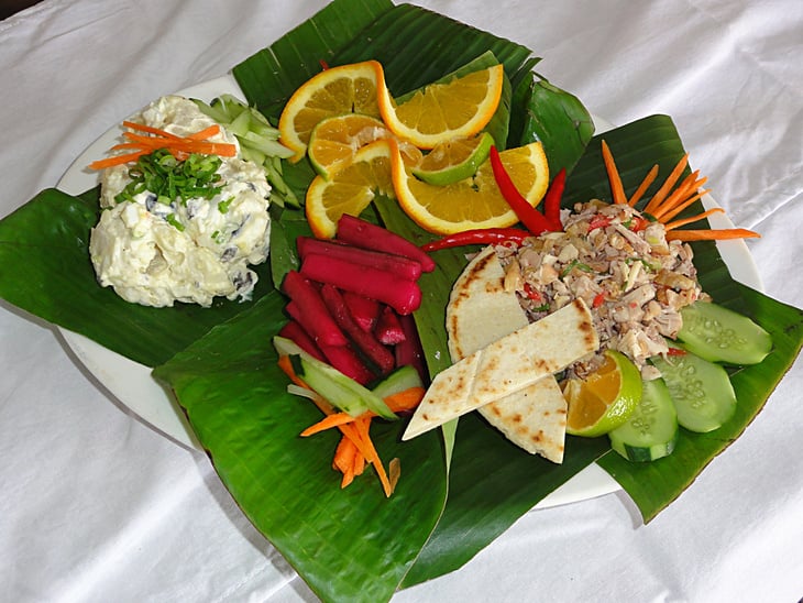 Chamorro cuisine- beef kelaguen and potato salad in banana leaves, top view